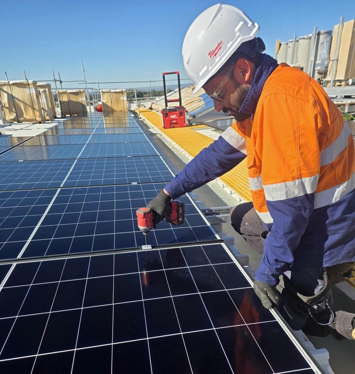 Image of a solar installer on a rooftop installing solar panels.